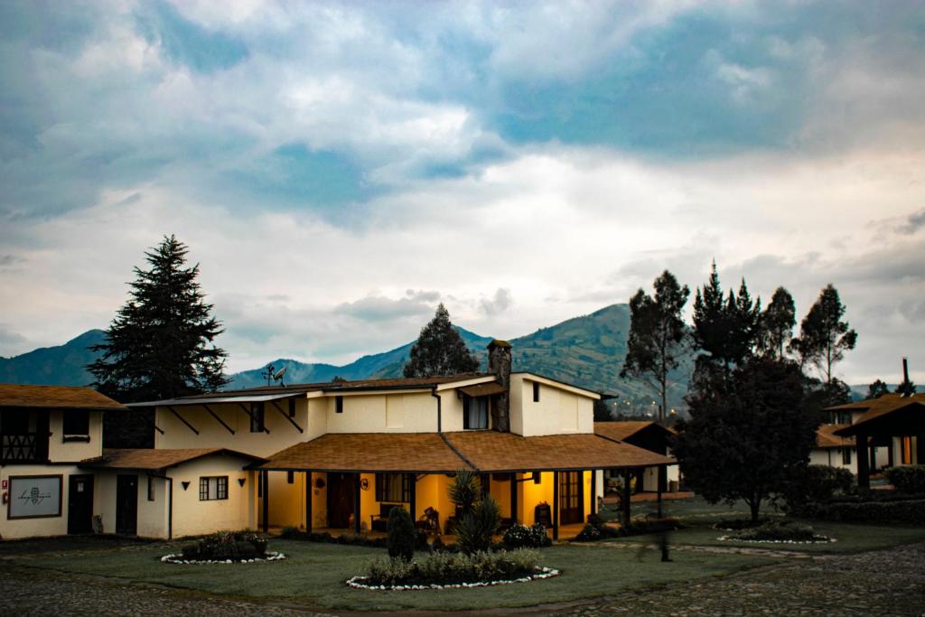 ein großes Haus mit Bergen im Hintergrund in der Unterkunft Chuquiragua Lodge & Spa in Machachi