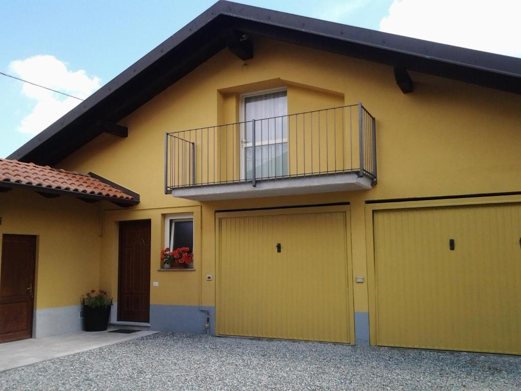 a yellow house with a balcony and two garage doors at La Mansarda Dell'Artista in Candelo