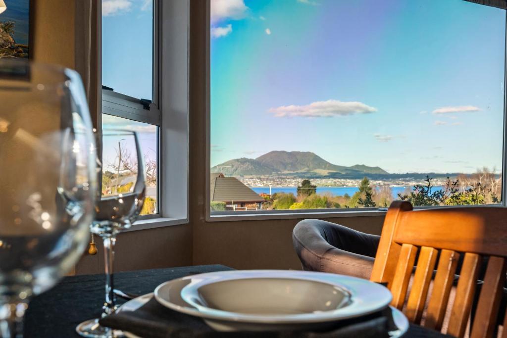 a table with a wine glass and a view of the ocean at Kinder Cottage - Taupo in Taupo