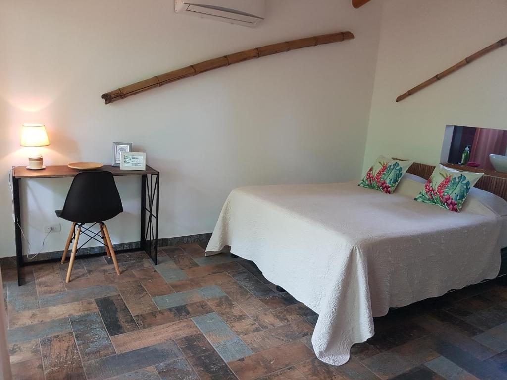 a bedroom with a bed and a desk with a lamp at Baliyana Lodge in San José Pinilla
