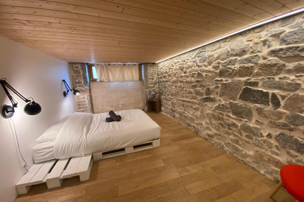 a bedroom with a bed and a stone wall at Le Rivet charmant 12 personnes Terreaux in Lyon