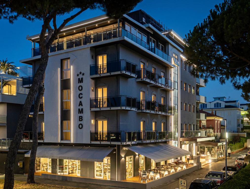 een groot wit gebouw met verlichting aan bij Hotel Mocambo in Riccione