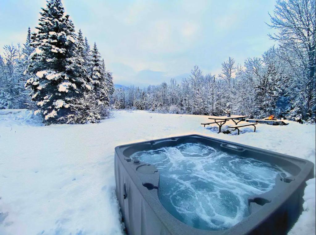 a hot tub in the snow next to a picnic table at Mountain View Log Cabin in Carroll