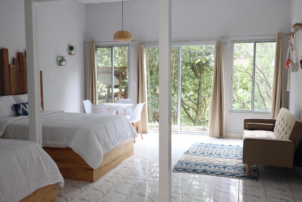 een witte slaapkamer met een bed en een glazen deur bij Boquete Firefly Inn in Boquete