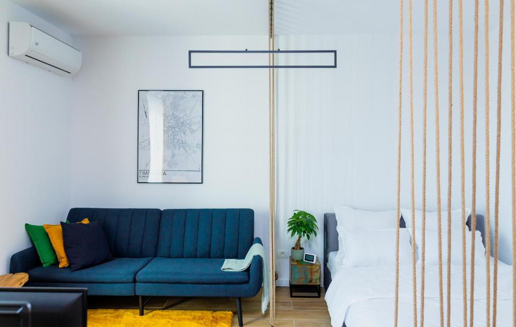 - un salon avec un canapé bleu et un lit dans l'établissement Vibrant Studio, à Timişoara