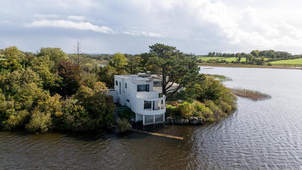 a white house on an island in the water at Lakehouse Inchiquin in Droíchead an Chláir