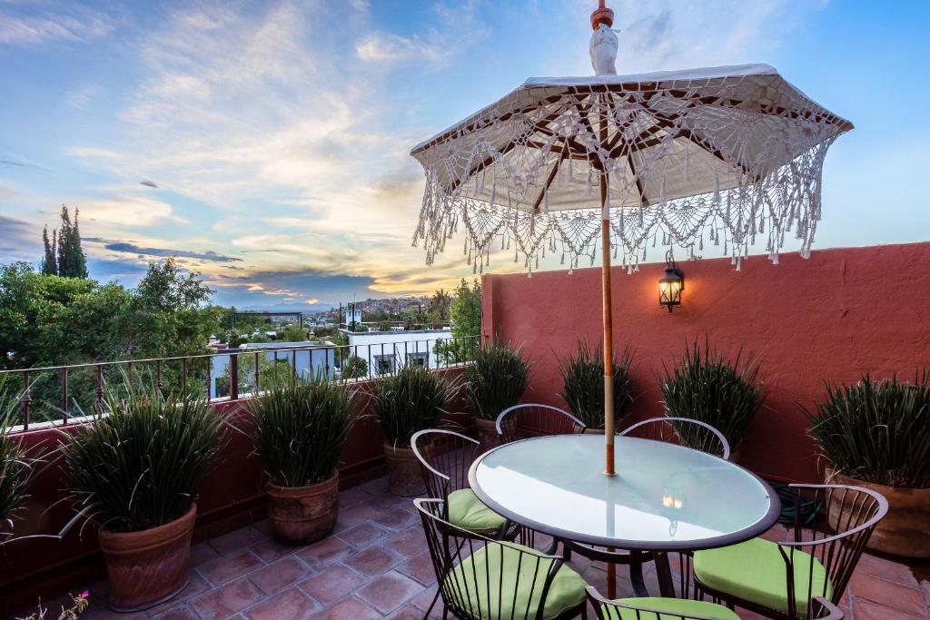 a patio with a table and chairs and an umbrella at 3BR Garden Home with Rooftop & Garage in Centro San Miguel de Allende in San Miguel de Allende
