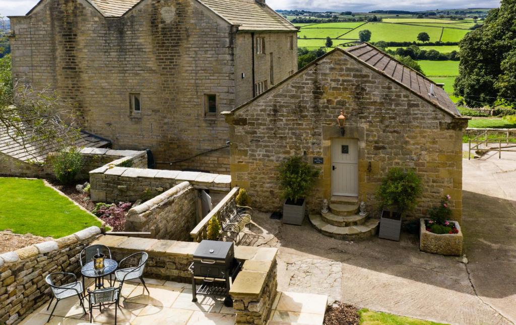 an external view of a stone building with a table and chairs at The Old Cooling House in Summer Bridge