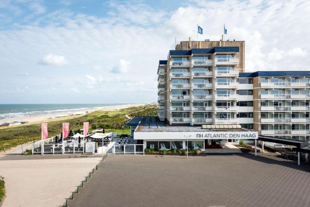 un hôtel sur la plage avec l'océan en arrière-plan dans l'établissement NH Atlantic Den Haag, à La Haye