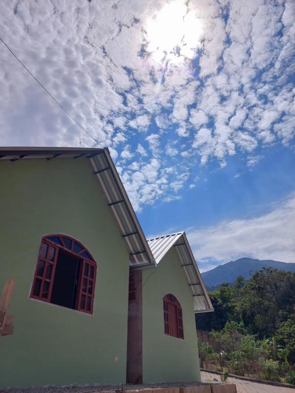 ein kleines Haus mit wolkigem Himmel im Hintergrund in der Unterkunft Mini lar próximo ao parque in Caparaó Velho