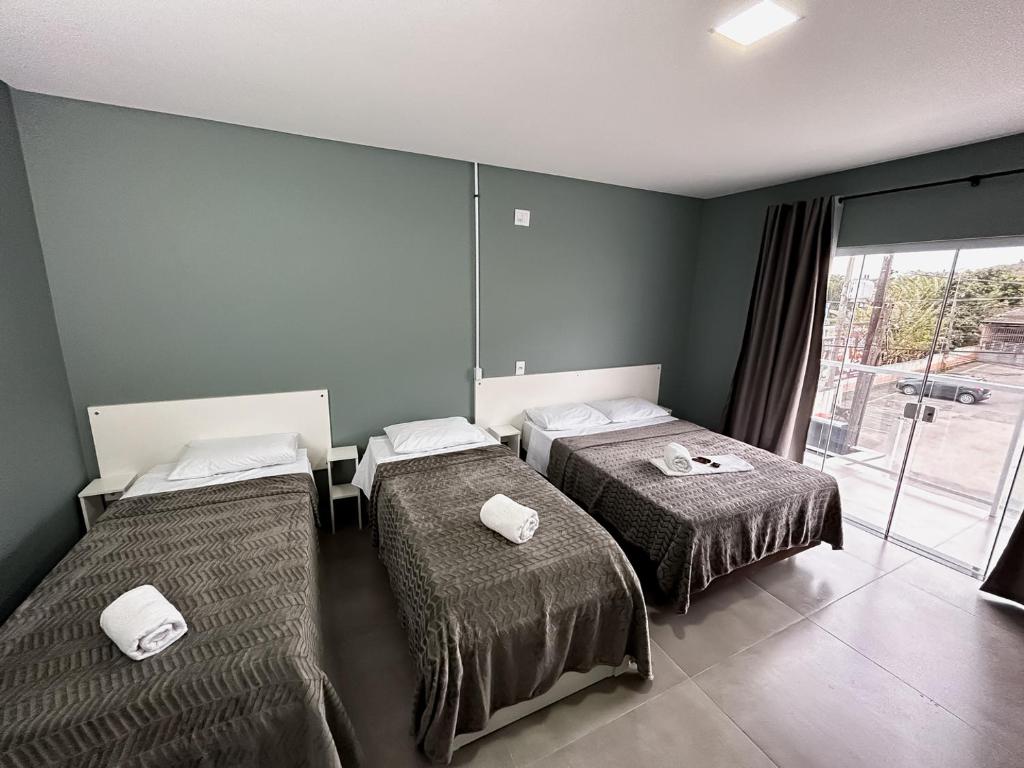 um quarto com 2 camas e uma grande janela em Pousada da Bia Praia em Penha