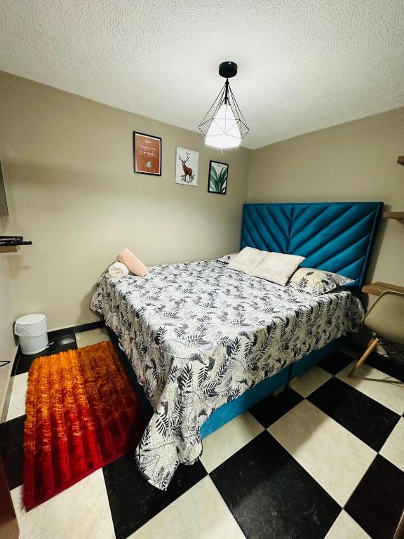 een slaapkamer met een blauw bed en een geruite vloer bij Aparta estudio cerca al aeropuerto el Dorado in Bogota