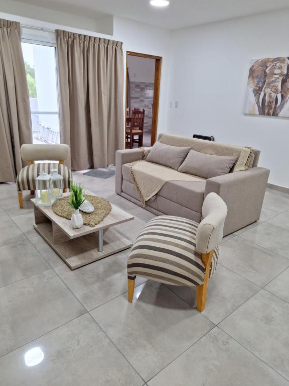 Una sala de estar con un sofá, una mesa y sillas. en CALA DEPARTAMENTO, en Alta Gracia