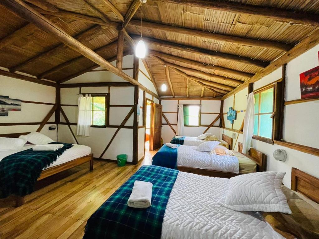 2 camas en una habitación con techos de madera en Cabañas Bambu Mindo, en Mindo