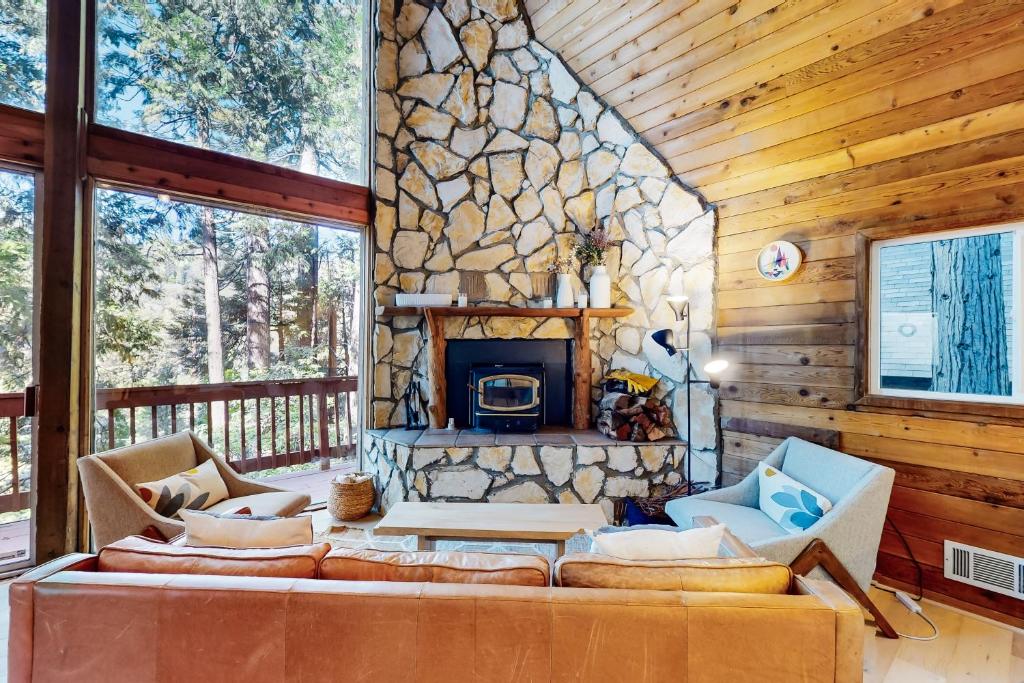 a living room with a stone fireplace in a cabin at Modern Pines Hideaway in Crestline