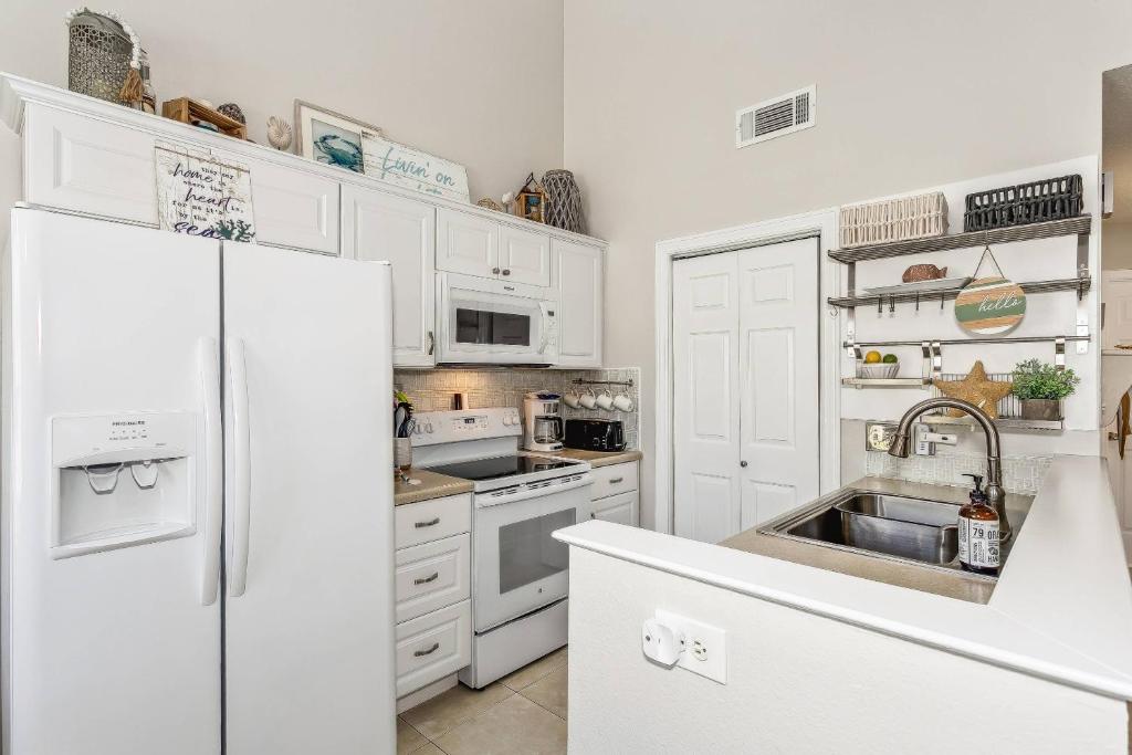 een witte keuken met een wastafel en een koelkast bij 3224 Birdseye Circle in Gulf Breeze