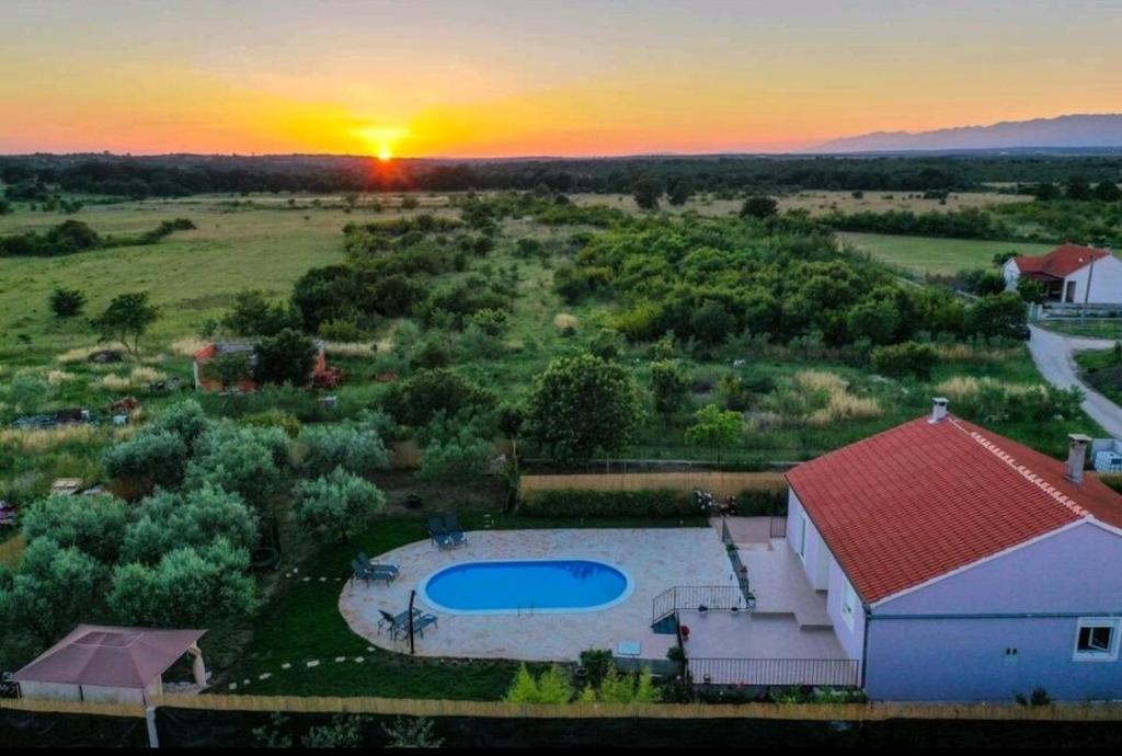 Gornji ZemunikにあるFamily friendly house with a swimming pool Zemunik Donji, Zadar - 21653のプール付きの家屋の頭上の景色と夕日を望めます。