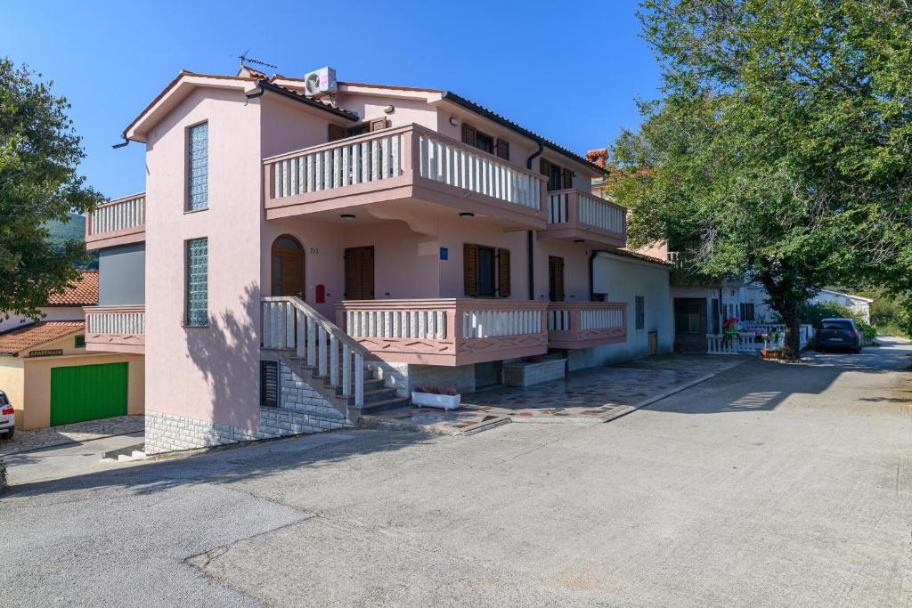 a pink house with a balcony and a driveway at Apartments by the sea Duga Luka - Prtlog, Labin - 2335 in Labin