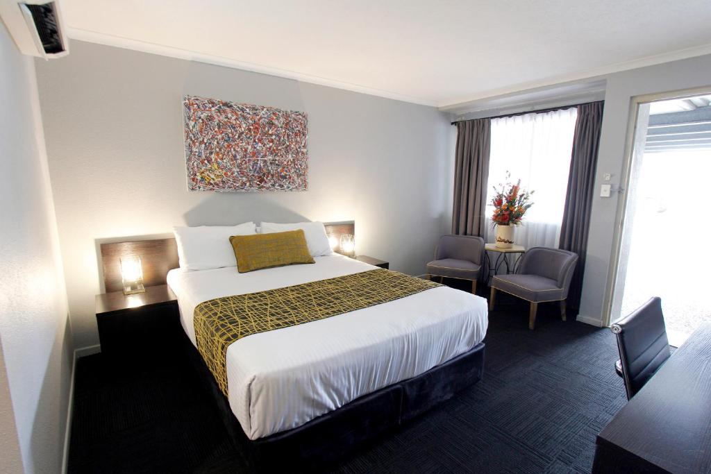 a hotel room with a bed and a table and chairs at The Stirling Motel in Rockhampton