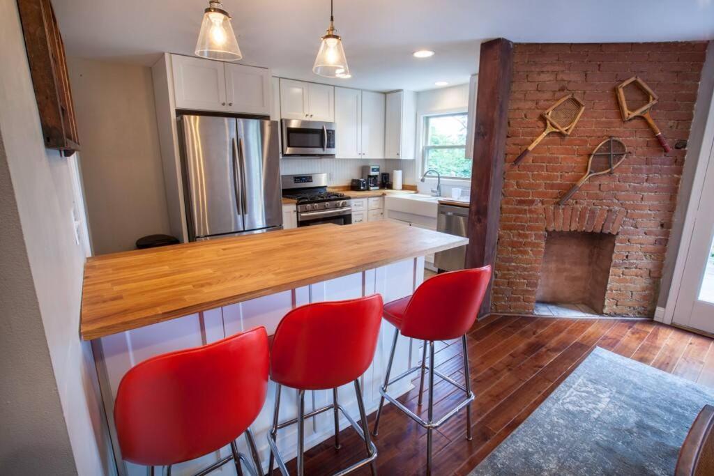 een keuken met een bar met rode stoelen en een open haard bij Light and Bright Renovated Farmhouse in the City in Pittsburgh