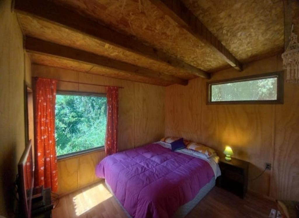 埃爾基斯科的住宿－Cabañas Isla Neruda，一间卧室设有紫色的床和窗户