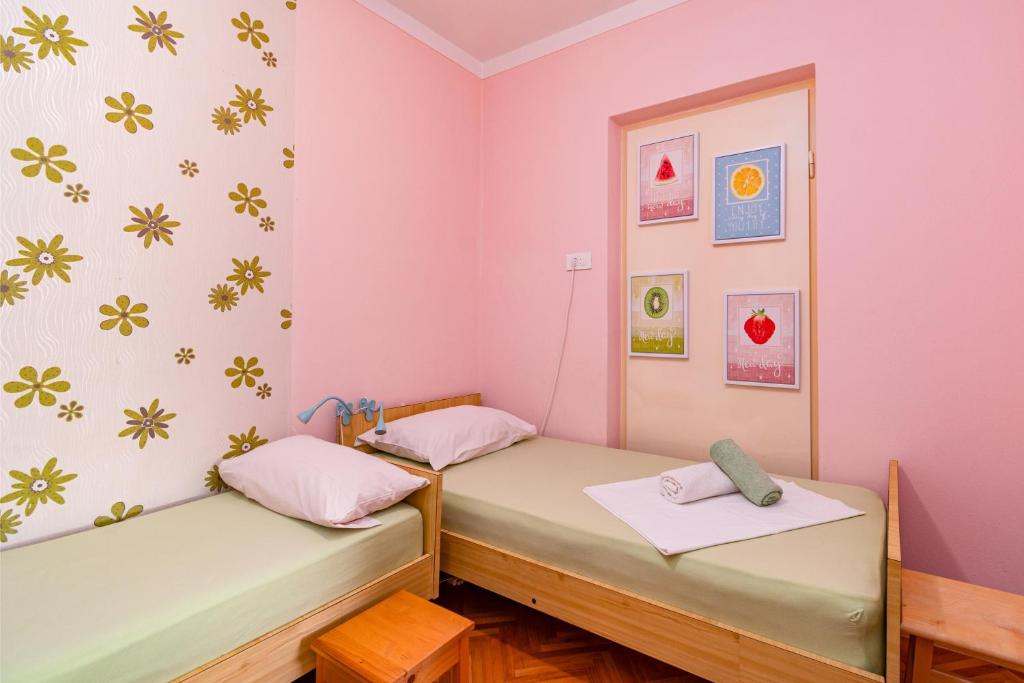 two beds in a room with pink walls at Apartments and rooms by the sea Banjol, Rab - 5077 in Rab
