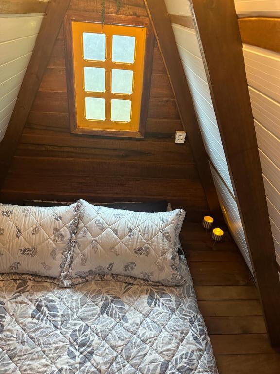 a bedroom with a bed and a window in a attic at Glamping casal - mini chale mobiliado com colchão casal roupa de cama travesseiros - Rancho Perene estação rural in Jaraguá do Sul