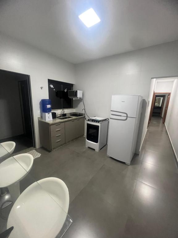 eine Küche mit einem weißen Kühlschrank sowie Tischen und Stühlen in der Unterkunft Residência Prado in Capitólio