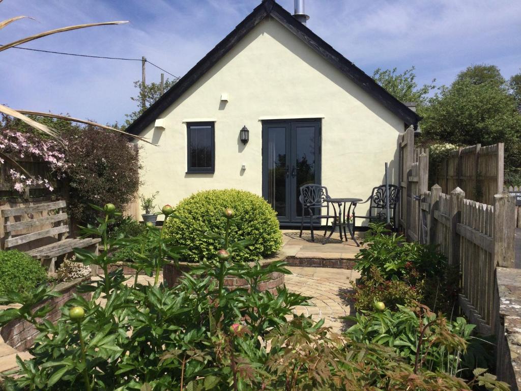 a small white house with a wooden fence at The Bothy in Bradworthy