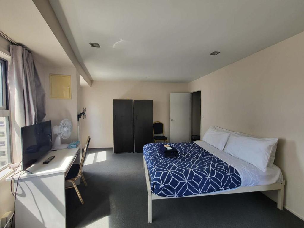 a bedroom with a bed and a desk with a computer at Empire Apartments in Auckland