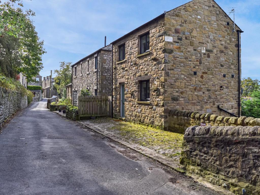 an old stone building with a fence next to a street at May Cottage - Uk12970 in Settle
