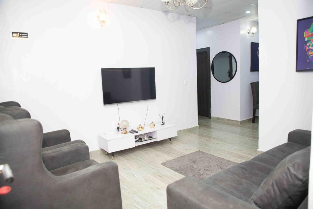 a living room with couches and a flat screen tv at Dabb Apartments in Ilorin