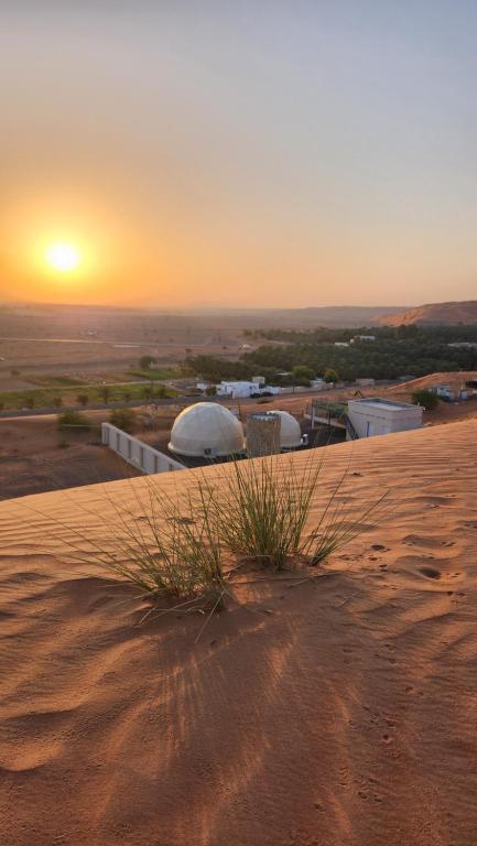 a sunset on top of a dune in the desert at Bidiyah Domes in Badīyah
