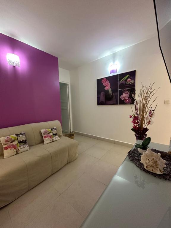 a living room with a couch and a purple wall at Appartement Coeur de Papillon in Baie-Mahault