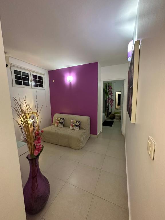 a living room with a couch and a purple wall at Appartement Coeur de Papillon in Baie-Mahault