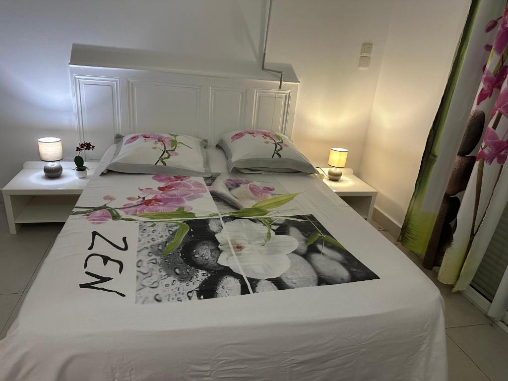 a bedroom with a bed with flowers on it at Appartement Coeur de Papillon in Baie-Mahault