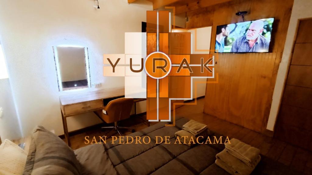 a room with a desk and a couch in a room at Hostal Yurak in San Pedro de Atacama