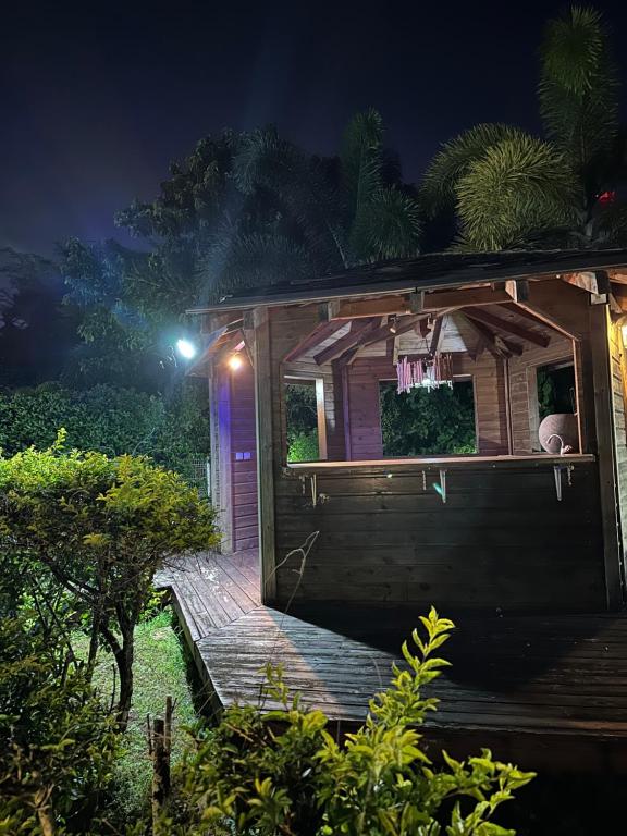 a small wooden house with a porch at night at Appartement Coeur de Papillon in Baie-Mahault