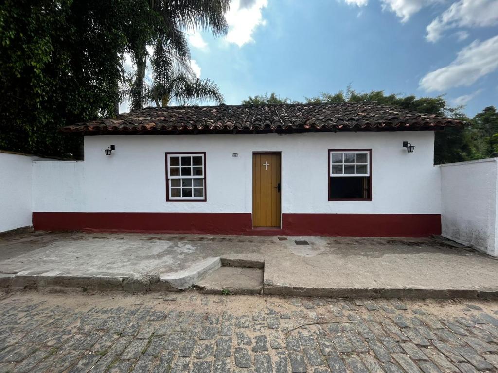 une petite maison blanche avec une porte marron dans l'établissement Casa do Chafariz Tiradentes, à Tiradentes