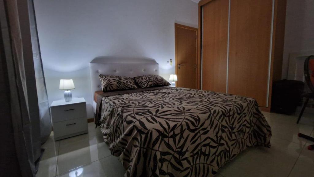 een slaapkamer met een bed met een zwart-wit dekbed bij Casa de férias com 2 quartos ou aluguer diária in Praia