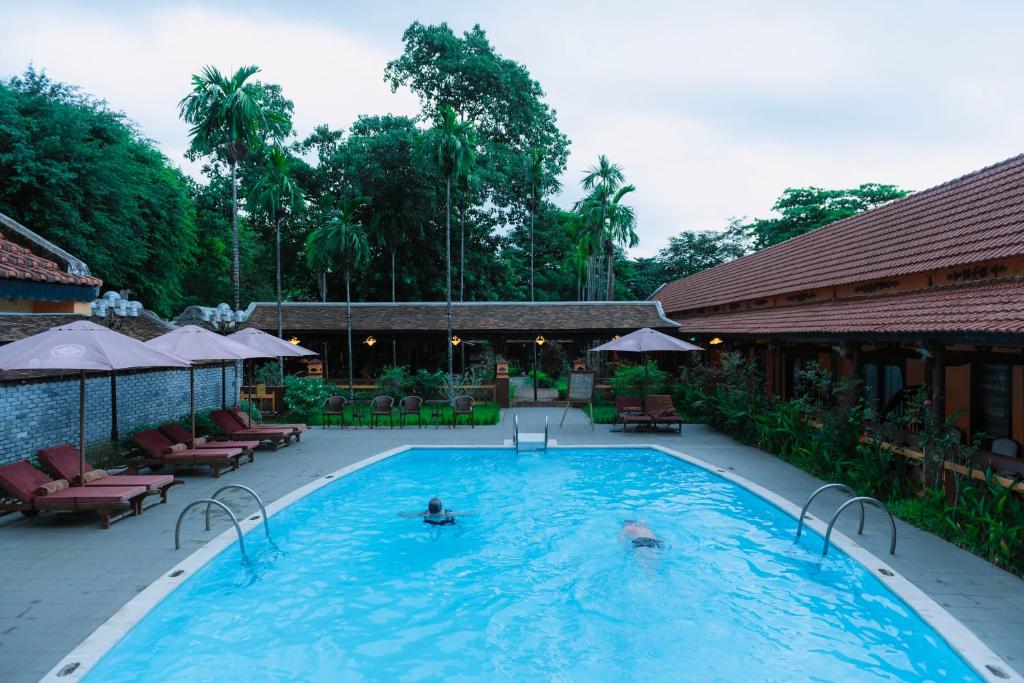 una gran piscina con 2 personas. en Spatel d'Annam - Imperial Boutique Spa & Hotel en Hue