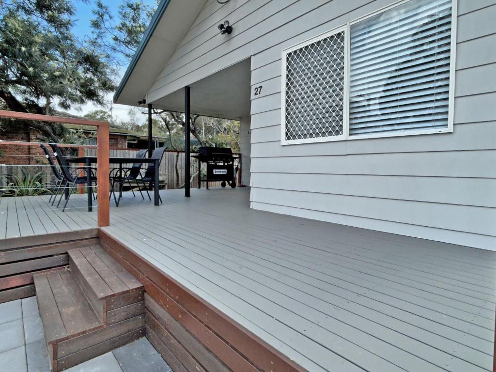 a deck with a table and chairs on a house at KIAMA AMITY POINT in Amity Point