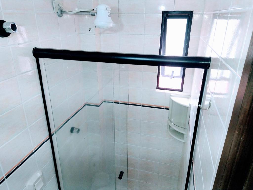 La salle de bains est pourvue d'une douche avec une porte en verre. dans l'établissement Triplex White em Caiobá-Matinhos-Pr a 200 mt do mar, à Matinhos