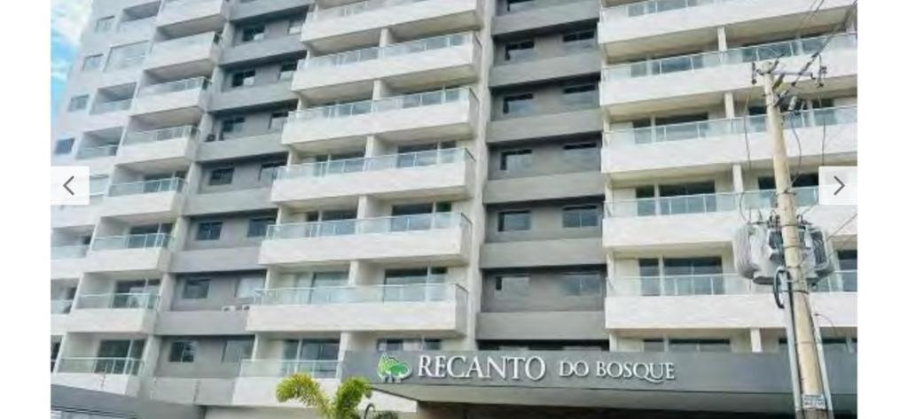 a tall apartment building with a sign in front of it at Condomínio Recanto do Bosque- Flat Service in Caldas Novas