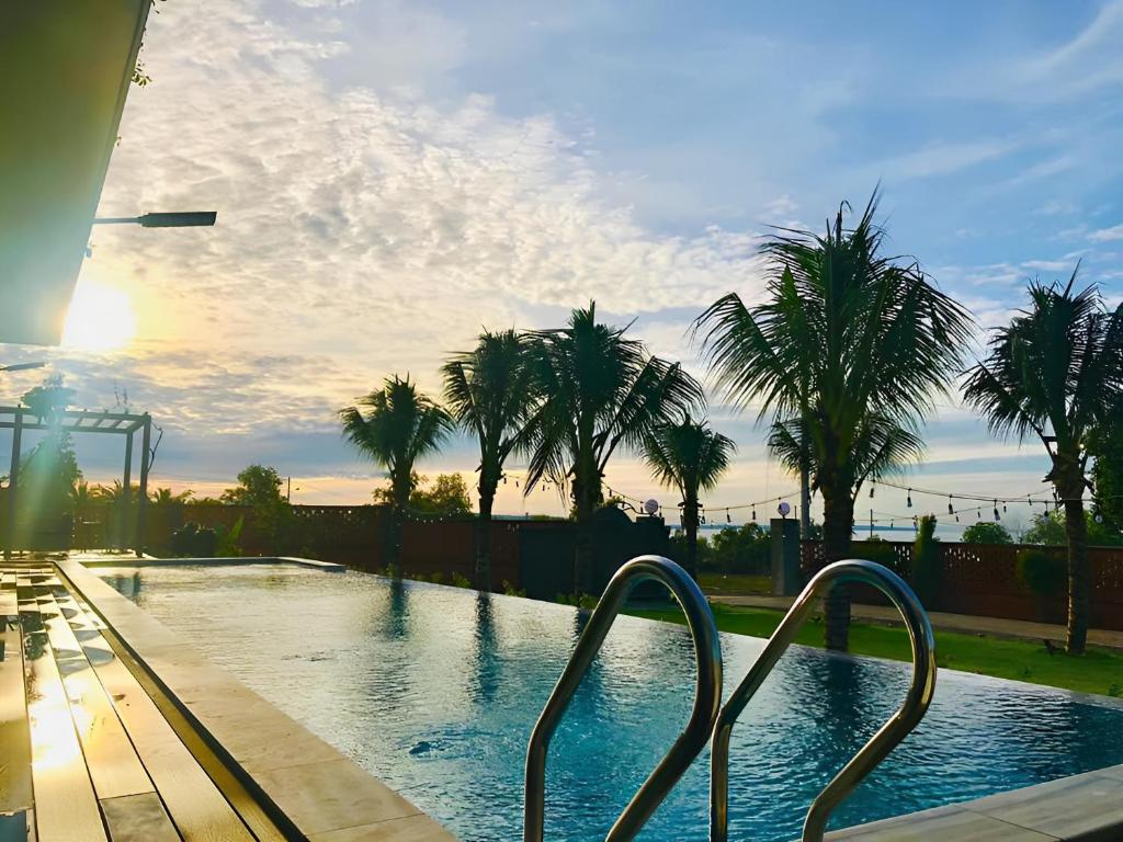 una piscina con palmeras en el fondo en Sunset Hill Villa Mũi Né en Phan Thiet