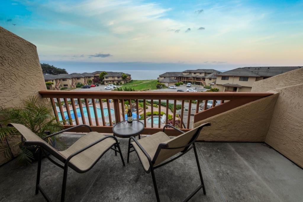 a balcony with chairs and a table with a view of the ocean at Seascape Ocean View Condo in Aptos