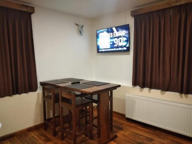 a room with a table and a television on a wall at Cabañas Angamos in Punta Arenas