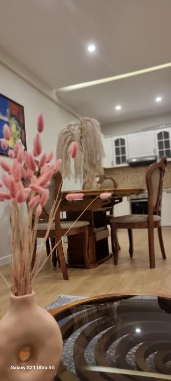 a living room with a table and a vase with pink flowers at Mina Apartment in Tirana