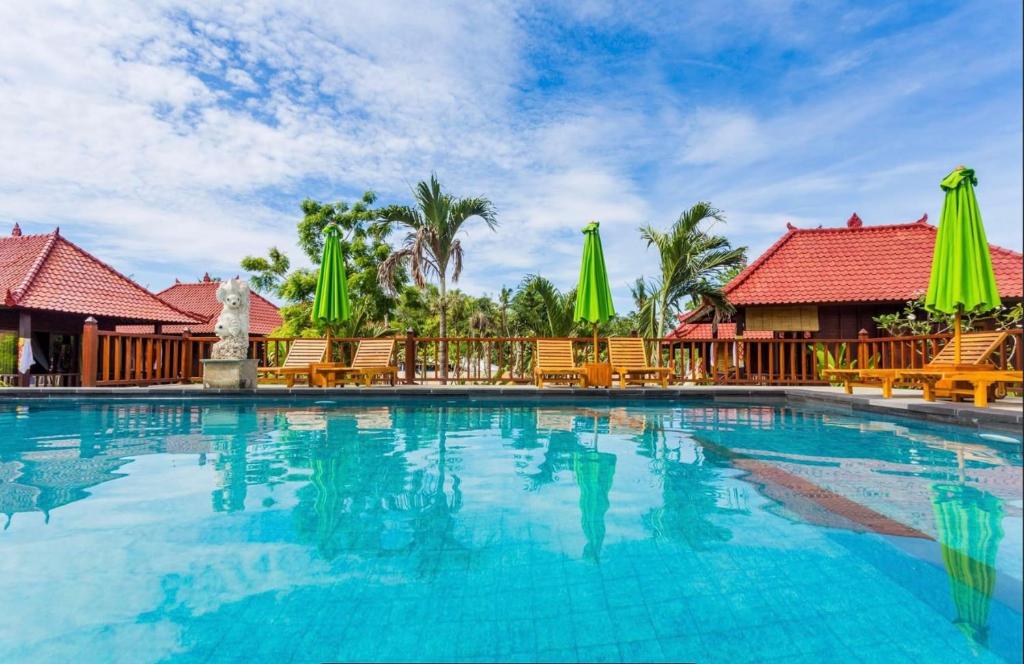 a swimming pool at a resort with chairs and umbrellas at Taman Sari Villa, Nusa Lembongan in Nusa Lembongan