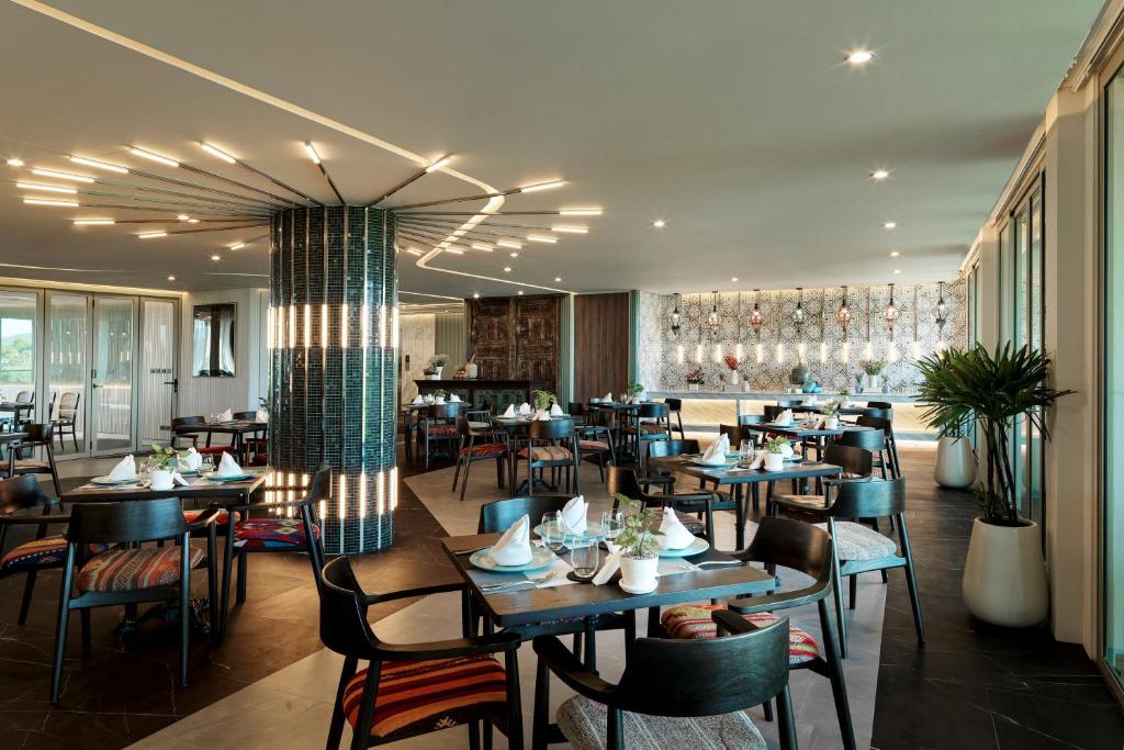a restaurant with tables and chairs in a room at Wyndham Grand Nai Harn Beach Phuket in Nai Harn Beach